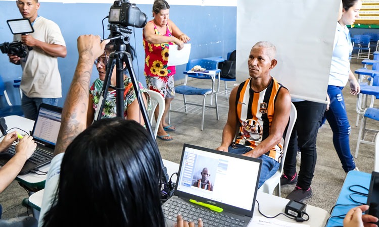 Funcionária do Detran atende um homem que tira foto para tirar a carteira de identidade