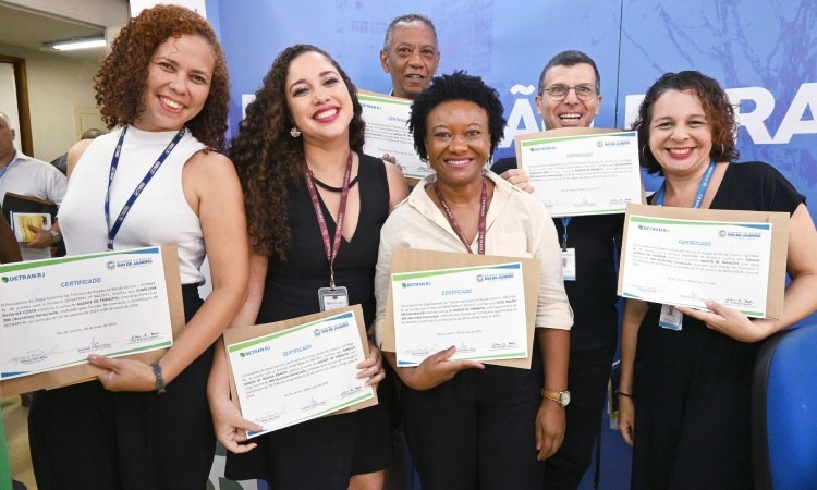 Seis novos agentes de trânsito, quatro mulheres e dois homens, mostram com orgulho seus certificados de formação do curso