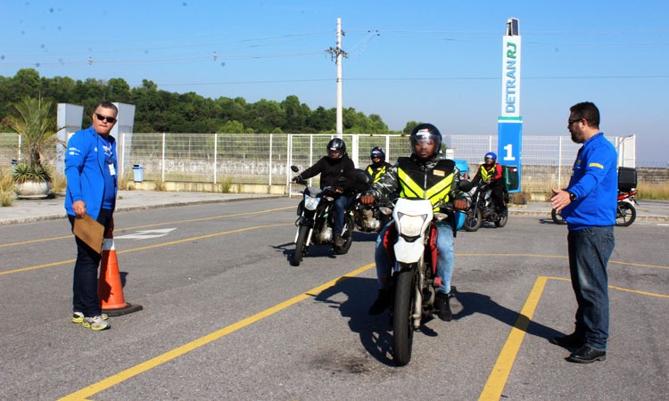 Quatro motofretistas, orientados por dois agentes do Detran, participam de curso prático em área do Detran.