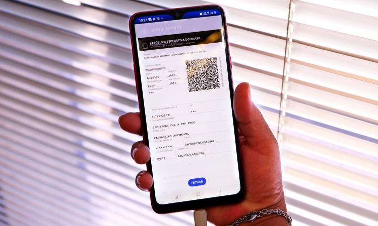 mão de um homem segurando um celular com imagem de boleto na tela