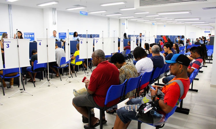 Cidadãos aguardam sentados serem chamados por atendentes do Detran, em área para serviços de habilitação