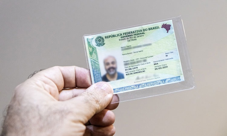 mão de um homem segurando uma Carteira de Identidade Nacional