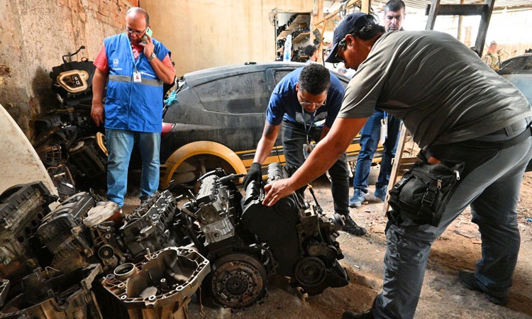 Agentes do governo verificam peças de carro dentro do ferro-velho