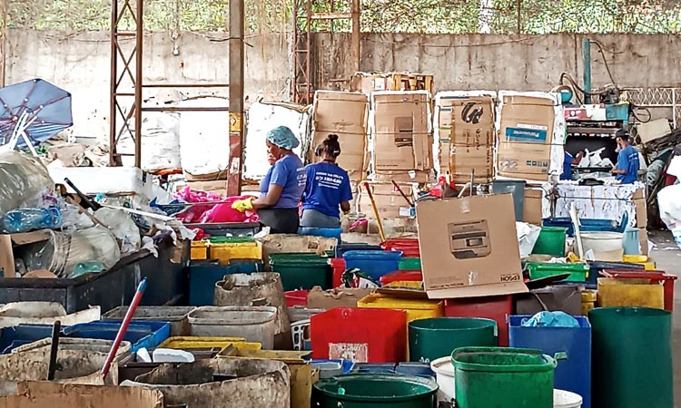 resíduos de reciclegem são separados por quatro pessoas em galpão