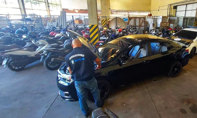 Agente da corregedoria do Detran verifica carro clonado com capô aberto