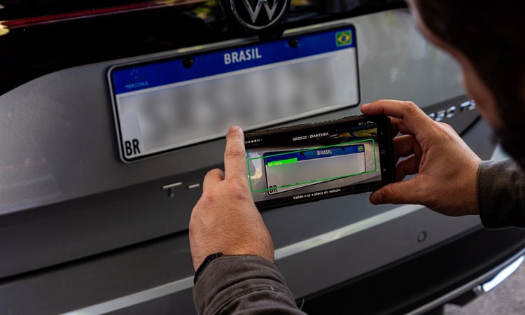 homem aponta câmera do celular para placa de veículo