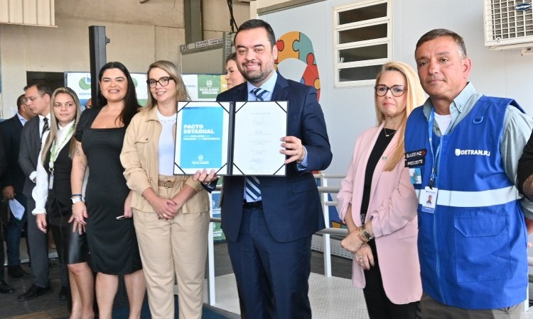 Governador do Rio de Janeiro, na presença de outros membros do governo, segura documento do Pacto Estadual pela Inclusão das Pessoas com Deficiência