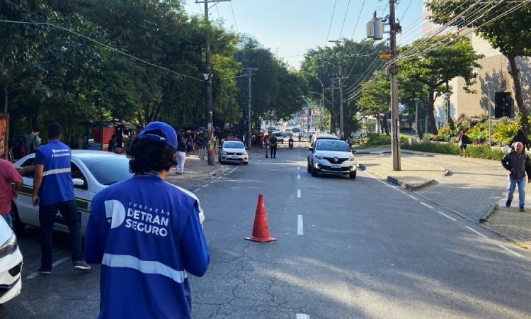 Agente do Detran, atrás de cone,  fiscaliza veículos que passam