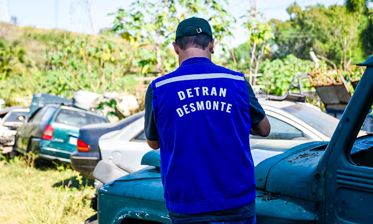 Agente do Detran RJ, de costas, fiscaliza as sucatas de veículos no depósito de um ferro-velho