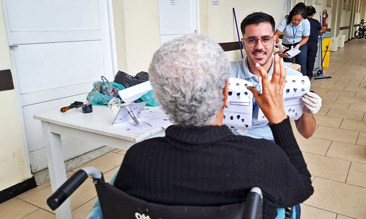 Funcionário do Detran RJ mostra as fichas com as impressões digitais de idosa na Casa São Luiz, no Caju