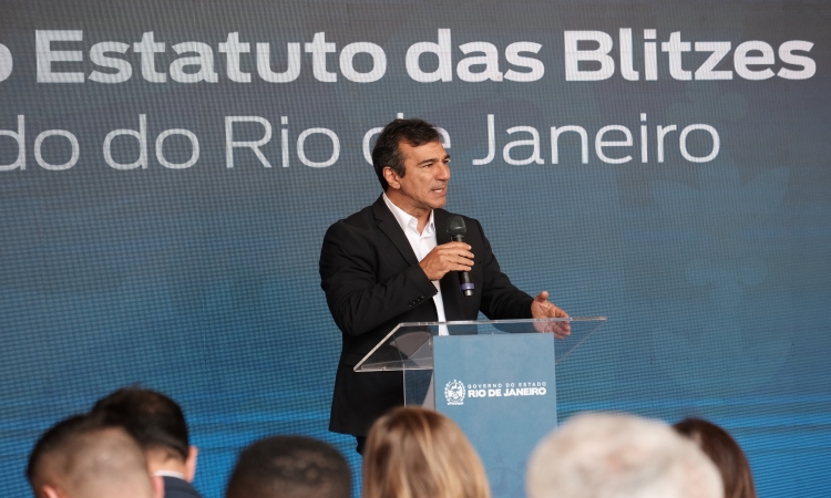 O presidente do Detran RJ, Vinicius Farah, discursa no Palácio Guanabara à frente de um painel com a frase "Criação do Estatuto das Blitzes"