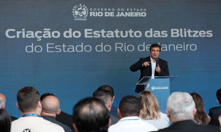 O presidente do Detran RJ, Vinicius Farah, discursa no Palácio Guanabara à frente de um painel com a frase "Criação do Estatuto das Blitzes"