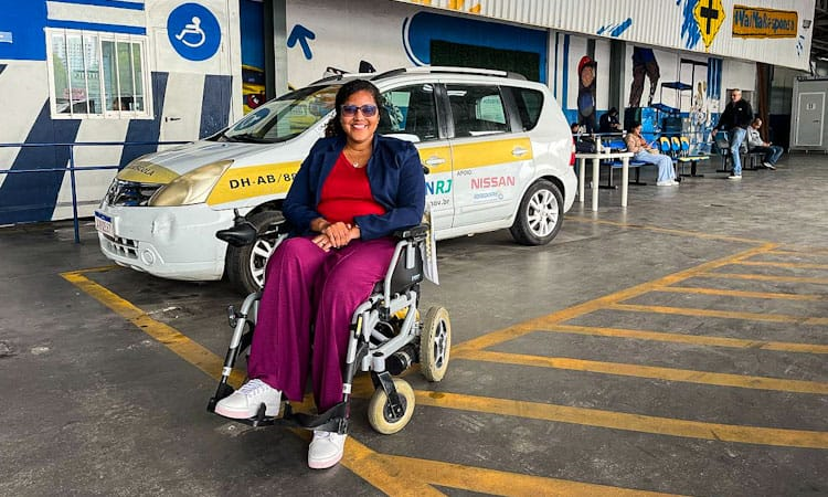 Thayná Araújo posa para foto na cadeira de rodas em frente ao carro adaptado do Detran RJ