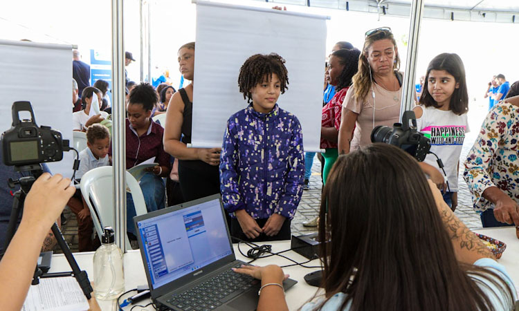Garoto fica em pé na cadeira para tirar foto durante o Detran Presente em Rio das Ostras