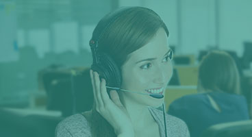 Funcionária do Detran, sorridente,  atende um senhor de óculos no guichê